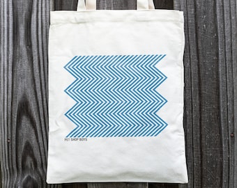 May include: A white tote bag with blue chevron pattern and the text "Pet Shop Boys" printed on the bottom.