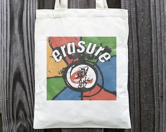 May include: A white canvas tote bag with a colorful graphic design featuring the word "Erasure" in a bold, black font. The graphic is a circle with a red, yellow, green, and blue design.