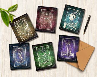 May include: A collection of tarot cards featuring intricate illustrations and titles like "The Sun," "The Lovers," and "The Fool." The cards have a vintage aesthetic with a dark border and are arranged on a light wooden surface.