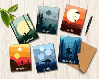 May include: A set of six rectangular greeting cards featuring stylized illustrations of fictional planets including Dagobah, Endor, Jakku, Tatooine, Hoth, and Mandalore. Each card displays a unique landscape, celestial bodies, and silhouettes, accompanied by a brown envelope.