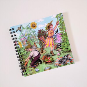 Pode incluir: Um caderno de espiral com uma ilustração colorida de uma cena de jardim. A ilustração apresenta uma estufa, uma pessoa colhendo vegetais, uma pessoa com um vestido listrado, um cachorro e um pássaro.