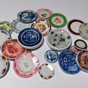 Op de afbeelding: Een verzameling miniatuur keramische borden met verschillende bloem- en geometrische patronen in tinten blauw, groen, rood, roze en wit.