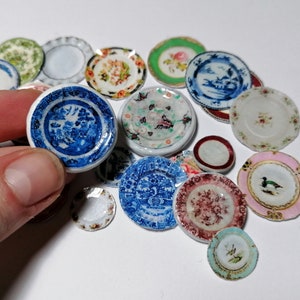 Op de afbeelding: Een verzameling miniatuur keramische borden met verschillende bloem- en geometrische patronen in blauw, roze, groen en wit.
