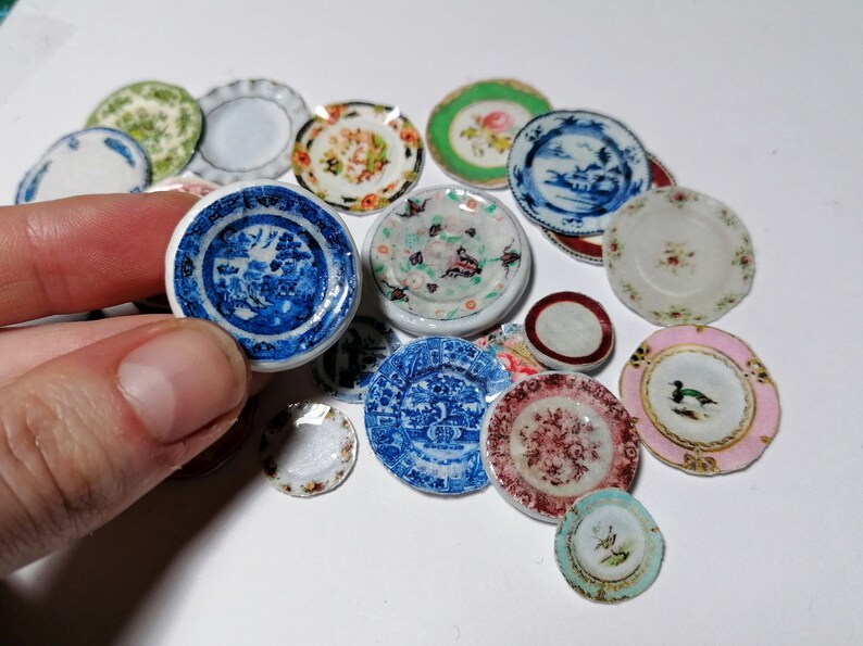 Op de afbeelding: Een verzameling miniatuur keramische borden met verschillende bloem- en geometrische patronen in blauw, roze, groen en wit.