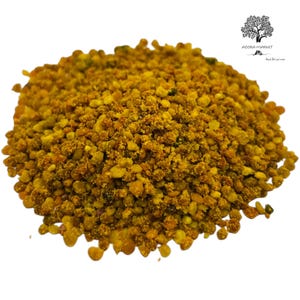 Puede incluir: Un montón de gránulos de polen de abeja que presentan una variedad de texturas y tonos amarillos, naranjas y marrones. Las partículas pequeñas, irregulares y redondeadas están agrupadas en un montículo. El logo de Agora Market es visible.