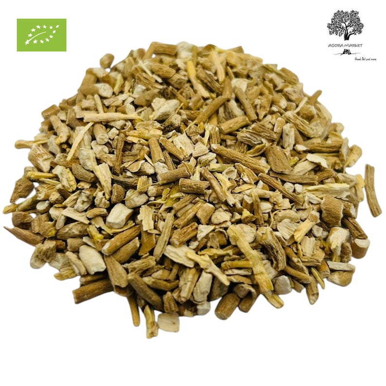 May include: A pile of dried, light brown herbal pieces, possibly roots or stems, fills the frame. The pieces vary in size and shape, with some appearing like small sticks. A green and white organic certification logo is in the upper left corner.