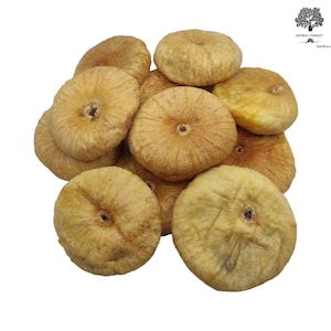 May include: A cluster of dried figs with a light tan, wrinkled skin and a flattened, circular shape. Each fig features a small, dark central opening. The logo for Agora Market is visible in the top right corner with a tree icon and text.