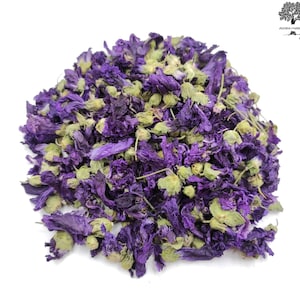 Può includere: Primo piano di un mucchio di fiori di ibisco secchi di colore viola. I fiori sono di un colore viola intenso e hanno una leggera sfumatura verde. Sono disposti in un mucchio sciolto, e alcuni dei fiori sono aperti, mentre altri sono chiusi.
