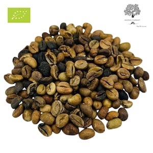 Può includere: Un mucchio di chicchi di caffè verdi non tostati con varie tonalità di marrone chiaro, marrone e carbone scuro. I chicchi hanno una superficie opaca e strutturata con un solco centrale visibile. L'immagine include un logo bio e un logo ad albero.