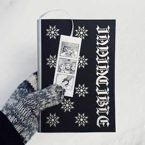 May include: A black book with a white snowflake pattern and the word "INDIVIDUALLY" printed vertically on the cover. A white photo strip bookmark with a black and white photo of three people is attached to the book.