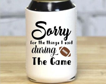 May include: White can cooler with a black and brown football design. The text reads "Sorry for the things I said during The Game".