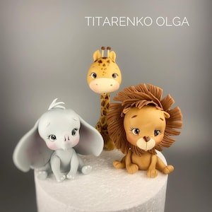 May include: Three adorable animal figurines made of fondant, perfect for a cake topper. A gray elephant, a brown lion with a mane, and a yellow giraffe with brown spots.