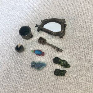 May include: Miniature fairy garden accessories including a small mirror with a wooden frame, a bucket, a spoon, a small bowl, a blue and red fish, a blue and green leaf, and a green rock. The items are made of resin and are designed for a fairy garden.