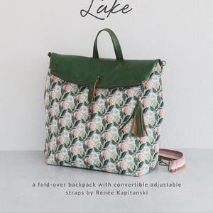 May include: A fold-over backpack with convertible adjustable straps. The bag features a green leather flap and handle, a floral pattern, and a tassel. The text "Lake" is written in cursive. The brand name "Sallie Tomato" is also visible.