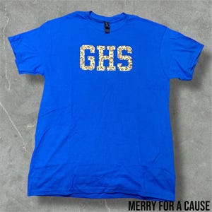 May include: A royal blue t-shirt with a white graphic of the letters "GHS" in a leopard print pattern.