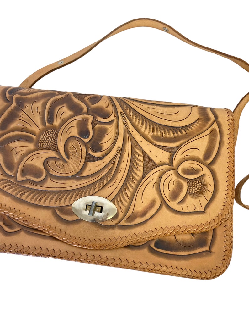 Peut inclure: Un sac &agrave; bandouli&egrave;re en cuir tann&eacute; avec un motif floral cisel&eacute; et un fermoir en laiton.