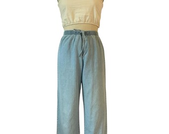 May include: A two-piece outfit displayed on a mannequin. The top is a cream-colored crop top with wide straps. The bottom is light blue denim, wide-legged, cropped pants with a drawstring waist. The outfit is casual and summery.