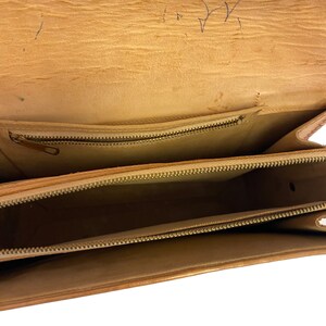 Peut inclure: L'int&eacute;rieur d'un sac en cuir marron avec deux compartiments &agrave; fermeture &eacute;clair. Le sac est vide.
