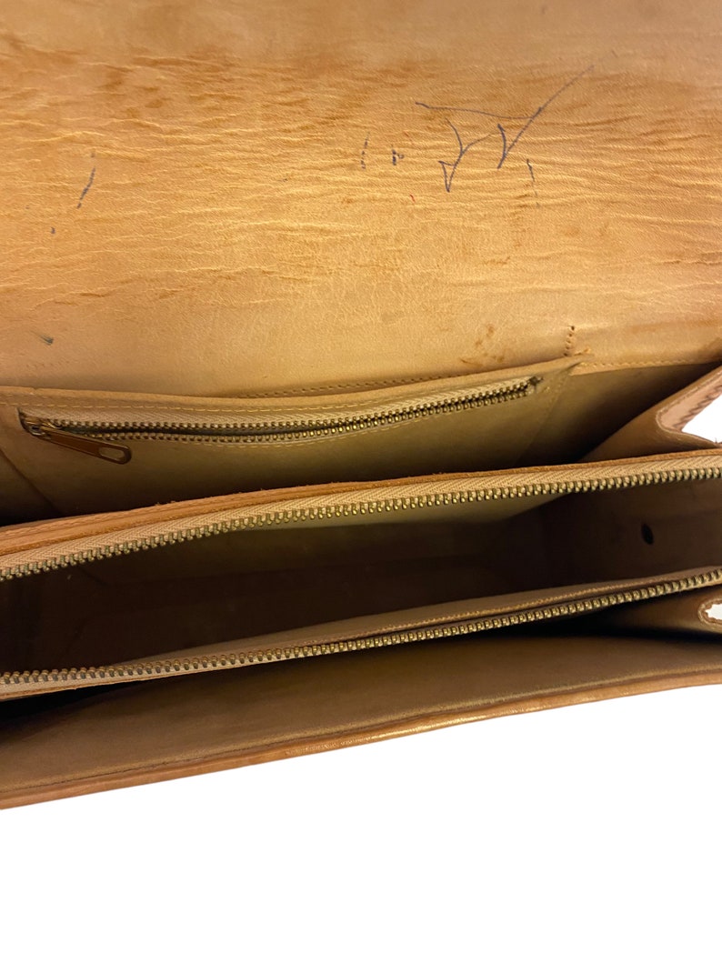 Peut inclure: L'int&eacute;rieur d'un sac en cuir marron avec deux compartiments &agrave; fermeture &eacute;clair. Le sac est vide.