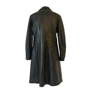 May include: A black leather coat with a classic design. The coat features a collared neckline, long sleeves, and a knee-length hem. The back view shows the coat's tailored fit and smooth texture.