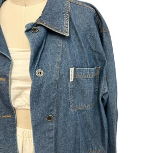 May include: A blue denim jacket with a button-up front and a single chest pocket. The jacket has a label that reads "ZARA" on the pocket.