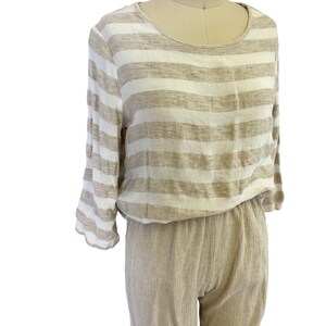 Puede incluir: Una camisa de manga larga a rayas y pantalones a juego en una combinaci&oacute;n de colores beige y blanco. La camisa tiene un escote redondo y los pantalones tienen un corte holgado.