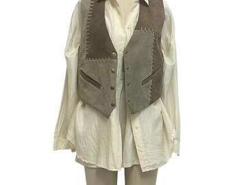 Könnte beinhalten: Eine Vintage-Wildlederweste in Braun- und Grautönen mit Patchwork-Design und Knopfverschluss. Die Weste ist über einem cremefarbenen Button-Down-Hemd geschichtet, wodurch ein Lagen-Look entsteht. Die Weste hat zwei Vordertaschen.