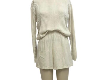 May include: A cream-colored, ribbed knit turtleneck sweater and matching shorts set. The long-sleeved sweater has a relaxed fit, and the shorts are high-waisted. The outfit is displayed on a mannequin.