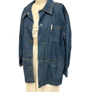 May include: A blue denim jacket with a button closure and two pockets. The jacket has a label on the left pocket that says "Lands' End".