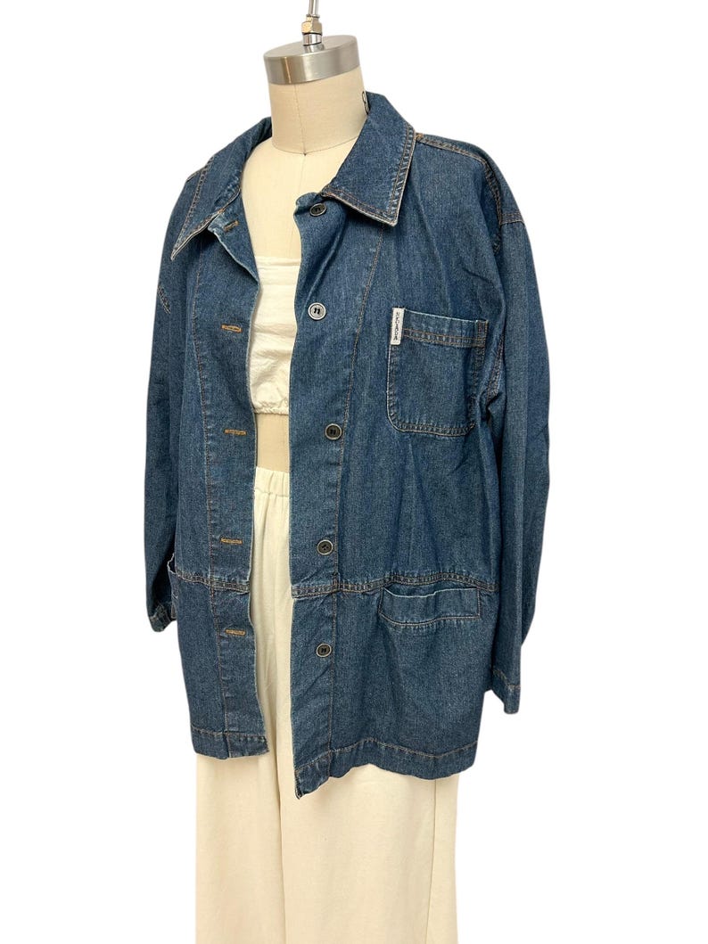 May include: A blue denim jacket with a button closure and two pockets. The jacket has a label on the left pocket that says "Lands' End".