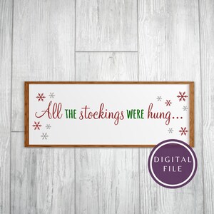 Op de afbeelding: Een wit houten bord met een bruin frame en de tekst "All the stockings were hung..." in rode en groene letters. Het bord is versierd met zilveren sneeuwvlokken.