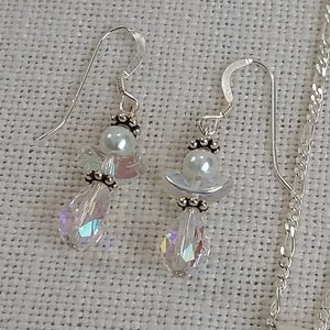 May include: A pair of silver earrings with iridescent crystal drops and white pearl accents. The earrings feature a delicate angel design.