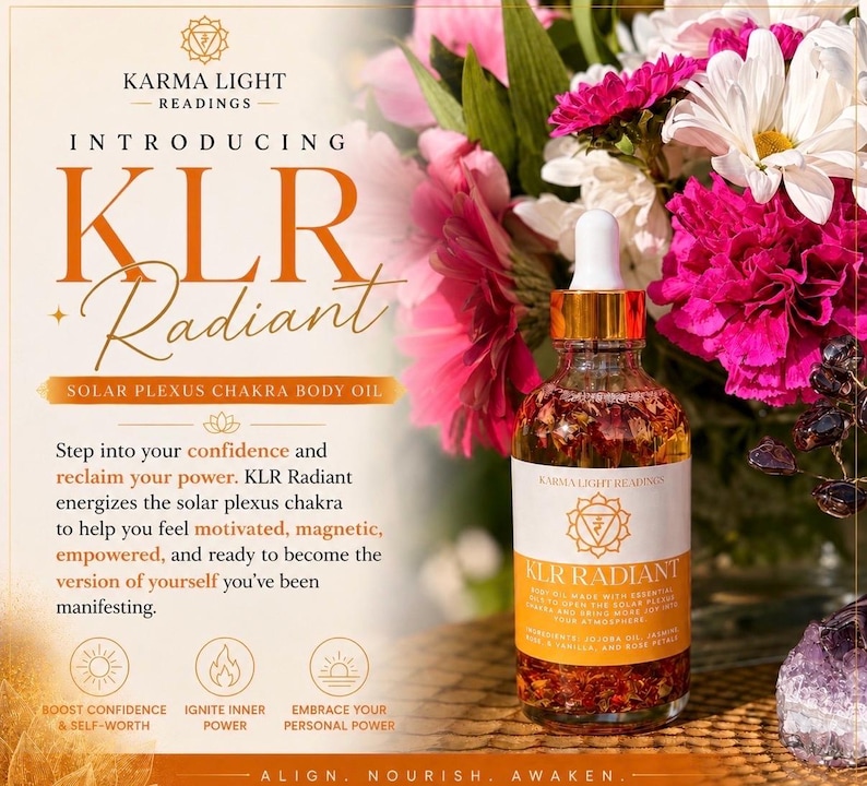 May include: A clear glass bottle of KLR Radiant Solar Plexus Chakra Body Oil with a gold dropper, set against a backdrop of pink and white flowers. The label reads "KLR Radiant" and "Solar Plexus Chakra Body Oil."