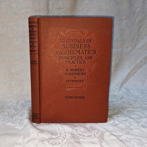 May include: A brown book titled "Essentials of Business Mathematics: Principles and Practice" by R. Robert Rosenberg, Intensive, Third Edition.