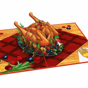 May include: A 3D pop-up card featuring a roasted turkey on a platter with cranberries, blueberries, and rosemary sprigs. The turkey is surrounded by a red and white checkered tablecloth on a wooden table. A gold fork and knife are on the table.