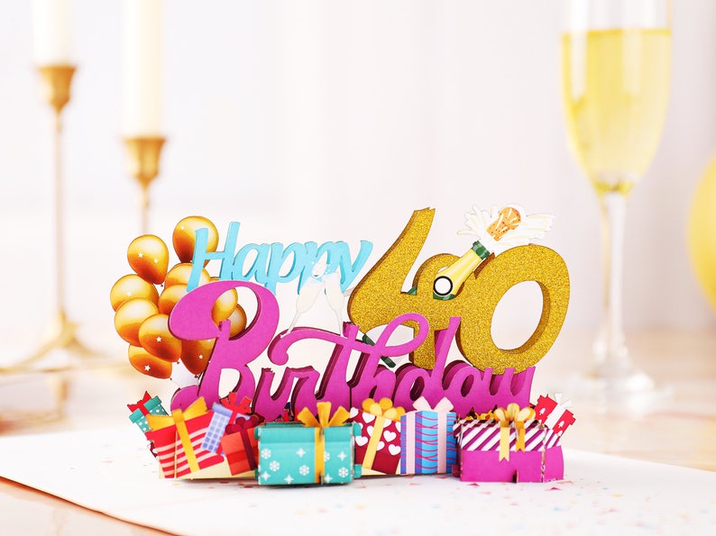 May include: A pink and gold 3D pop-up card with the words "Happy 40th Birthday" and gold balloons. The card features a champagne bottle and a gold glitter 40.