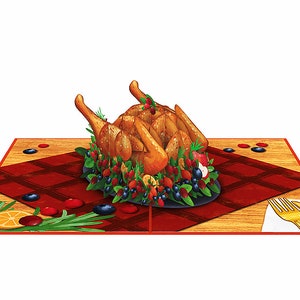 May include: A 3D pop-up card featuring a roasted turkey with a cranberry and blueberry sauce, surrounded by rosemary sprigs and orange slices. The turkey is on a black plate and a red and white checkered tablecloth. A gold fork and knife are on a white napkin on a wooden table.