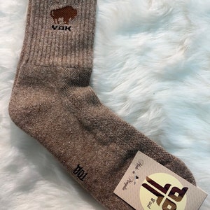 Könnte beinhalten: Ein Paar braune Wollsocken mit einem braunen Büffel-Logo oben. Die Socken sind in der Mongolei hergestellt und bestehen aus 100% Wolle.