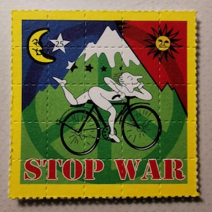 May include: A yellow, green, red and blue psychedelic blotter paper with a cartoon image of a person riding a bicycle with the words "STOP WAR" printed in red.