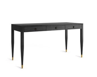 May include: A black wooden desk with three drawers and gold accents. The desk has a rectangular top and four legs.