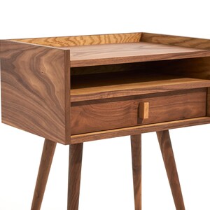May include: A wooden nightstand with a drawer and a shelf. The nightstand has a dark brown finish and four legs.