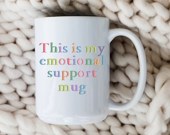 May include: White ceramic mug with the text "This is my emotional support mug" in rainbow colors.