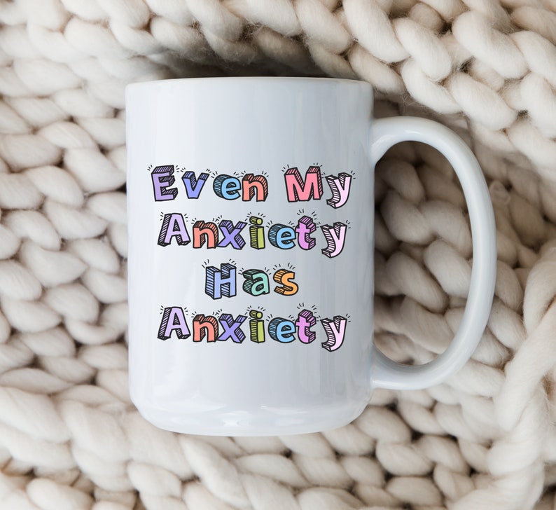 May include: White ceramic mug with a colorful, cartoon-style design that reads "Even My Anxiety Has Anxiety".