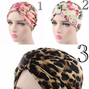 May include: Three different styles of turban head wraps. The first is a pink and white floral print, the second is a cream and pink floral print, and the third is a black and brown leopard print.