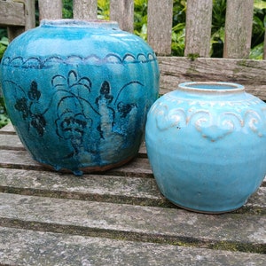 May include: Two blue ceramic vases with intricate designs. The larger vase has a floral pattern and the smaller vase has a geometric pattern.