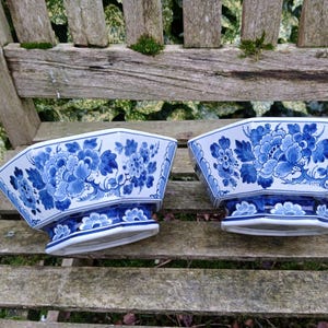 May include: Two blue and white porcelain decorative bowls with floral designs. The bowls are octagonal and have a raised base.