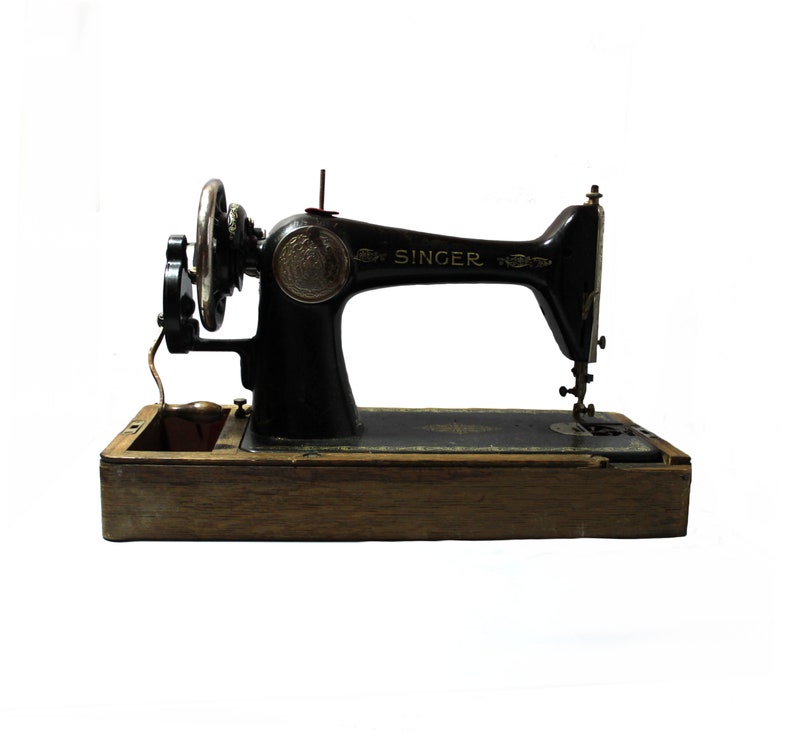 May include: Vintage Singer sewing machine, black with silver accents, set on a wooden base. The word "SINGER" is prominently displayed. The machine features a hand wheel, needle, and other sewing components.