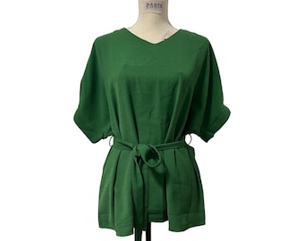 Puede incluir: Una blusa verde con mangas cortas y cuello en V, con cinturón a juego. La prenda se exhibe en un maniquí y tiene un corte holgado. El cinturón define la cintura y las mangas están dobladas. La tela es de color liso.