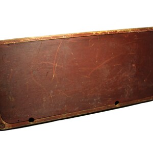 May include: Rectangular, vintage-style wooden sign with a distressed, reddish-brown surface. The sign has a gold-colored metal frame and visible screw details. The wood shows signs of wear and tear.