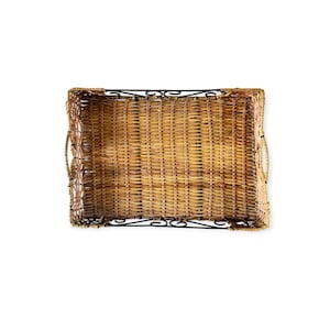 Op de afbeelding: Rechthoekige geweven rieten dienblad met een donkerbruine metalen basis en handgrepen. De dienblad heeft een natuurlijke bruine kleur en een geweven patroon. De metalen basis heeft decoratieve krullen. De dienblad is leeg.